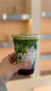 Here are a few options for your alt text, depending on the focus of the image:

**Option 1 (Focus on the drink):**
"Cherry and white chocolate matcha drink at the new Made UK cafe in Leeds."

**Option 2 (Descriptive):**
"A matcha latte with cherry and white chocolate toppings at Made UK cafe opening in Leeds."

**Option 3 (Lifestyle focus):**
"Hand holding a cherry and white chocolate matcha drink at the new Made UK cafe in Leeds city centre."

**SEO Tip:** Option 1 is generally the strongest for SEO as it includes the brand name, the product, and the location.