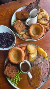 Here are a few options for your SEO alt text (all under 125 characters):

**Option 1 (Descriptive):**
Delicious beef Sunday roast with Yorkshire pudding and gravy at The Shamrock Social in Nottingham.

**Option 2 (Focus on location):**
A hearty beef roast dinner served with vegetables and stout gravy at The Shamrock Social, Nottingham.

**Option 3 (Concise):**
Sunday roast beef dinner with all the trimmings at The Shamrock Social pub in Nottingham.