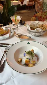 A first-person vlog review of The Ivy in Exeter, featuring a date night experience. The video captures the exterior, the interior ambiance, a variety of cocktails, and several courses including gnocchi, lobster risotto, salmon, and desserts like creme brulee and cookie dough.