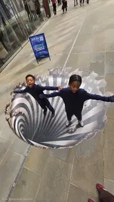 A family visits a 3D street art installation near St. Paul's Cathedral in London, which serves as a promotional teaser for the upcoming Museum of Illusions.