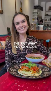 A creator visits Harmonize Cafe, a vegan social enterprise in London. The video features a tour of the space, shots of the food (dahl, flatbread, banana bread), and an introduction to the owner and the cafe's 'pay what you can' model.
