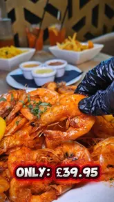 Here are a few options for your SEO alt text, keeping under the 125-character limit:

**Option 1 (Descriptive):**
Big 50 Feast at Prawn Theory featuring 50 prawns, chips, rice, trio of sauce, and a jug of mojito for £39.95.

**Option 2 (Action-oriented):**
Prawn Theory’s Big 50 Feast deal featuring prawns, chips, rice, and mojito jug available Mon, Wed, and Fri for £39.95.

**Option 3 (Concise):**
Table spread of Prawn Theory’s Big 50 Feast deal including 50 prawns, sides, and a mojito jug for £39.95.