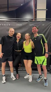 Three people in activewear posing, two holding Pizza Express pizza slices, at Hyrox Cardiff.
