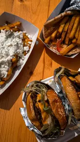 Here are a few options for your alt text, depending on what is shown in the specific image:

**Option 1 (Best for a spread of food):**
"A delicious spread of street food including loaded fries, tacos, and pizza at The Halfway food festival in Llanelli."

**Option 2 (Best for a specific food item):**
"A portion of golden, crispy garlic and parmesan tater tots from Y Bocstatws at The Halfway street food festival."

**Option 3 (Generic/General):**
"Local street food vendors and a variety of delicious dishes at The Halfway food festival in Llanelli, Wales."

**SEO Tip:** Alt text should be descriptive and include the location (Llanelli) and keywords (street food) to help with search rankings. I have kept these under 125 characters.