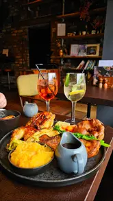 Here are a few options for your SEO alt text, depending on the specific focus of the photo:

**Option 1 (Focus on the meal):**
"Close up of a delicious Sunday roast dinner with beef, chicken, Yorkshire pudding and sides at Brewstone in Uplands, Swansea"

**Option 2 (Focus on the restaurant vibe):**
"A table full of hearty Sunday roast dinners inside the cozy, brick-walled Brewstone restaurant in Uplands, Swansea"

**Option 3 (Concise & SEO-focused):**
"Sunday roast dinner with beef and chicken served at Brewstone restaurant in Uplands, Swansea"

**Best practice tip:** If the photo shows a specific dish (like the beef or chicken), choose the option that best describes the main visual focus. All of these are under 125 characters.