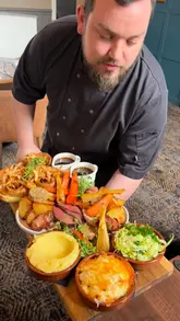 A short, handheld clip featuring a chef presenting a large, loaded roast dinner platter directly to the camera.