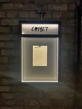 A clean, well-composed, and functional shot of a restaurant menu board mounted on a brick wall, effectively establishing the venue's identity and setting.