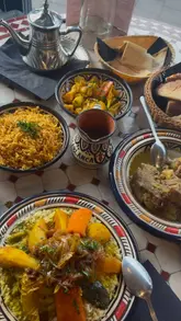 Here are a few options for your SEO alt text, depending on the focus of the image:

**Option 1 (Focus on the food spread):**
A delicious spread of authentic Moroccan dishes including lamb tangia, chicken couscous, and mint tea at Casablanca Cardiff.

**Option 2 (Focus on the restaurant experience):**
Authentic Moroccan dining experience featuring a variety of traditional dishes and mint tea at Casablanca on Albany Road.

**Option 3 (Concise & descriptive):**
Table full of traditional Moroccan cuisine, including lamb, couscous, and baklawa, served at Casablanca restaurant Cardiff.

**SEO Tip:** If the image shows a specific dish, make sure to name that dish first (e.g., "Lamb Tangia and chicken couscous served at Casablanca restaurant in Cardiff").