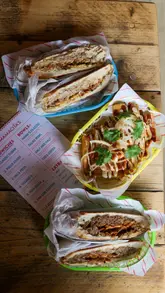 A montage of shots featuring the interior decor, specifically the murals, and various food items like Cuban sandwiches and fries at a restaurant called Mamacita's.