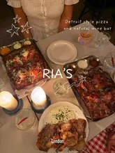 Here are a few options for your SEO alt text, keeping under the 125-character limit:

**Option 1 (Descriptive & SEO-focused):**
Group of friends enjoying Detroit-style pizza and cocktails at Rias London, a cozy restaurant in Notting Hill.

**Option 2 (Action-oriented):**
Girls dinner featuring Dave’s hot pepperoni pizza and sides at Rias, a trendy pizza and wine bar in Notting Hill.

**Option 3 (Keyword-heavy):**
Detroit-style pizza and cocktails at Rias in Notting Hill, the perfect spot for a cozy girls dinner in London.