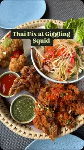 Here are a few options for your alt text, depending on what is most prominent in the photo:

**Option 1 (Focus on the meal):**
A delicious spread of Thai food at Giggling Squid in Leicester, featuring green curry, pad thai, and a seafood feast.

**Option 2 (Focus on the restaurant experience):**
Friends enjoying a vibrant Thai lunch with papaya salad and curry at Giggling Squid in St Martins Square, Leicester.

**Option 3 (SEO-focused):**
A colorful feast of Thai Green Curry and seafood at Giggling Squid, one of the best Thai restaurants in Leicester.

**Tip:** Choose the one that best matches the specific layout of the food on the table!