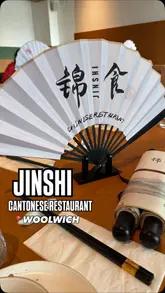 A review-style video showcasing a visit to Jinshi, a modern Chinese restaurant in Woolwich. The video features the exterior, the cozy interior, the menu, and a variety of dishes including dumplings, shredded beef, black bean pepper beef, roasted meats, and noodle soup.
