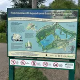 A clear, informative photograph of the information sign at Rickmansworth Aquadrome, detailing the layout, wildlife, and rules of the nature reserve.