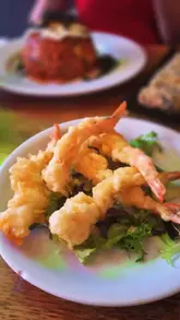 A montage-style video showcasing various Korean dishes including king prawn tempura, seaweed rolls, and bibimbap, alongside shots of the restaurant's interior, specifically the hanging umbrella decor.