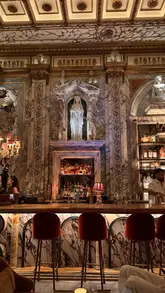 Here are a few options for your SEO alt text, keeping them under 125 characters:

**Option 1 (Descriptive):**
Stunning Greek-inspired interior of Apollo’s Muse, a hidden bar in London with dramatic sculptures and atmospheric lighting.

**Option 2 (Keyword-focused):**
Intricate Greek mythology decor inside Apollo’s Muse, a hidden cocktail bar and lounge in London, UK.

**Option 3 (Concise):**
Dramatic, luxurious interior design at Apollo’s Muse, a hidden bar located in London.

**SEO Tip:** Since alt text is primarily for accessibility and search engines, **Option 1** is your best bet as it describes both the vibe and the specific location.