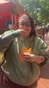 A short vlog-style video featuring a visit to a food market. The creator showcases a mushroom Philly sandwich being prepared and eaten, followed by a taste test of churros with vegan chocolate sauce.
