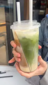 Here are a few options for your alt text, keeping it under 125 characters:

**Option 1 (Descriptive & SEO friendly):**
A split cup holding a white chocolate matcha latte and a Spanish latte from Slrp Coffee in Kingston Upon Thames.

**Option 2 (Focusing on the trend):**
The viral split cup drink featuring matcha and Spanish latte at Slrp Coffee, Kingston Upon Thames.

**Option 3 (Concise):**
Two-compartment split cup filled with matcha and Spanish latte at Slrp Coffee in Kingston.