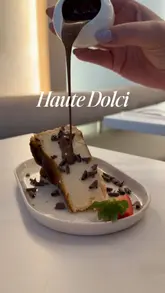 A short, aesthetic reel showcasing various desserts and brunch dishes at Haute Dolci. The video features slow-motion close-ups of chocolate being poured over cheesecake and the Matilda cake, as well as shots of Eggs Benedict and a Lotus Biscoff dessert. The video is set to music and includes text overlays.