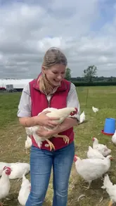 A personal vlog-style video featuring a woman on a farm discussing self-sufficiency and sourcing poultry. The video includes shots of the farm, the chickens, the preparation of meat, and a finished roasted chicken on a BBQ.