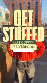 Here are a few options for your SEO alt text, keeping it under 125 characters:

**Option 1 (Descriptive):**
A person holding a gourmet sandwich while standing in a trendy independent coffee shop in Liverpool.

**Option 2 (Focus on the series):**
A resident posing with a sandwich as part of a series highlighting the best food spots in Liverpool city centre.

**Option 3 (Concise):**
Close-up of a delicious sandwich being held in a popular Liverpool cafe, showcasing local city food culture.
