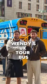 The video features two creators visiting the Wendy's Frosty Funhouse pop-up bus in Glasgow. They walk through the various interactive stations, including a ball pit, hair braiding, tooth gems, a photo booth, and a game of Frosty Pong, while highlighting the opportunity to win prizes and get free Frosty treats.