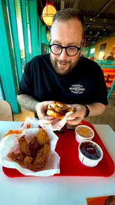 The creator visits a Popeyes location, providing a walkthrough of the ordering process and a taste test of their chicken burger, tenders, and biscuit with various sauces.