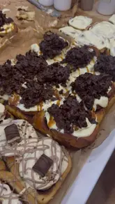 A short, visually focused reel showcasing various cinnamon buns from a pop-up stall called The Brownie Stack. The video features close-up shots of the toppings and textures of the baked goods.