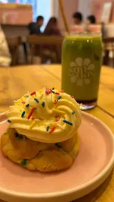 A short, handheld video showcasing a visit to a vegan cafe called Sunday. The video features shots of the cafe exterior, a table spread of various drinks and cookies, a close-up of a cookie being broken, and a shot of a dog inside the venue.