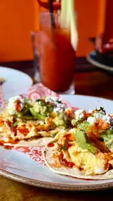 Here are a few options for your SEO alt text, keeping under the 125-character limit:

**Option 1 (Descriptive):**
Vegetarian Desayuno tacos and a refried bean burrito for Sunday brunch at The Basement in Edinburgh.

**Option 2 (Focus on the food/vibe):**
Delicious Mexican-inspired vegetarian Sunday brunch dishes and cocktails at The Basement restaurant in Edinburgh.

**Option 3 (Concise):**
Vegetarian brunch tacos and burritos with a Bloody Maria cocktail at The Basement, Edinburgh.