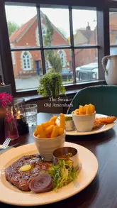 A montage showcasing the interior and food at The Swan in Old Amersham, featuring shots of steak, fish and chips, and the pub's decor.