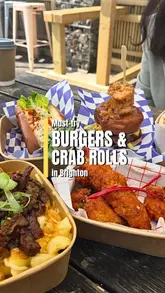 Here are a few options for your alt text, depending on what is most visible in the image:

**Option 1 (Focus on the meal/brand):**
"Surf N Turf burger, crab roll, and mac’n’cheese from Puffin at Tempest on Brighton beach."

**Option 2 (Descriptive & SEO-friendly):**
"Selection of smash burgers and seafood dishes from Puffin at Tempest Brighton on a sunny day."

**Option 3 (Short & punchy):**
"A spread of burgers, crab rolls, and mac’n’cheese on an outdoor table at Puffin, Brighton."

**SEO Tip:** Always try to include the location (Brighton) and the main subject (Puffin/burgers) as those are the keywords people will be searching for.