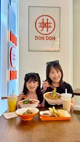 A short, energetic reel showcasing a £5 donburi offer at Don Don London in Vauxhall. The video features a variety of Japanese dishes including Wagyu and Ibérico pork donburi, handmade bao, tempura, takoyaki, and milk teas, with the creators enjoying the meal in a casual dining setting.