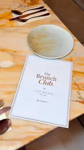 Here are a few SEO-friendly alt text options, depending on the focus of the image:

**Option 1 (Focus on the food - recommended):**
Delicious steak and eggs with sourdough and berry French toast served at The Brunch Club by Café Begum in Manchester.

**Option 2 (Focus on the atmosphere):**
Elegant neutral interiors and marble tables at The Brunch Club by Café Begum, a luxury brunch spot in Manchester.

**Option 3 (Comprehensive):**
A spread of gourmet brunch dishes including steak, eggs, and berry French toast at The Brunch Club by Café Begum.