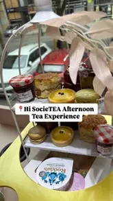 Here are a few options for your SEO alt text, keeping it under 125 characters:

**Option 1 (Descriptive):**
Delicious afternoon tea with cakes and prosecco served on the pink and gold Hi SocieTEA double-decker bus in Liverpool.

**Option 2 (Focus on the experience):**
Friends enjoying an afternoon tea experience with singing waiters on the Hi SocieTEA moving bus in Liverpool city centre.

**Option 3 (Concise):**
Afternoon tea set with sandwiches, scones, and prosecco on the luxurious pink Hi SocieTEA bus tour in Liverpool.