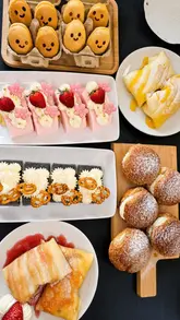 A review of Candy's Dream Cake in Aberdeen, featuring a variety of savoury dishes like dandan pork noodles, Hong Kong hotdogs, and panko prawns, followed by an extensive selection of cakes and pastries including mango pancakes, strawberry cream cake, and matcha/black sesame cakes. The video highlights the warm atmosphere and the community connection through a wall of customer messages.