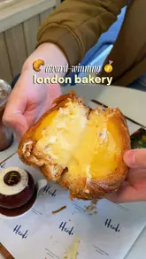 A creator visits a new bakery location in Richmond, showcasing a variety of pastries, quiches, and cakes. The video features close-up shots of the food, the bakery's interior, and the creator tasting the items, highlighting the quality and award-winning nature of the products.