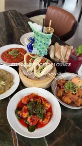 A montage video showcasing the interior, food, and drinks at Tarshish, a rooftop restaurant. The video features various dishes including bao buns, skewers, and a dessert, alongside shots of the venue's decor and sunset views.