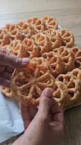 A step-by-step recipe video demonstrating how to make 'Spicy Kokis,' a Sri Lankan snack, using rice flour, coconut milk, curry leaves, and chilli flakes. The video uses clear, top-down shots to guide the viewer through the mixing and frying process.