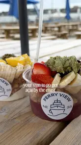A short, aesthetic montage showcasing açai bowls and coffee at a waterside kiosk venue called Ferry View. The video highlights the fresh food, the outdoor seating area, and the scenic location by the ferry landing.