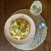 A high-quality, overhead shot of a homemade crab and lemon mafaldine pasta dish served with a glass of white wine. The composition is clean and well-styled, focusing on the texture of the pasta and the fresh garnish.