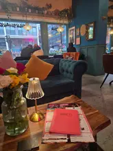 A moody, atmospheric shot of a table setting at Gran T's Coffee House, featuring a menu, a small table lamp, and a vase of flowers, capturing the venue's cosy evening ambiance.