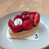 A high-quality, well-lit close-up shot of a strawberry mascarpone tart on a simple plate, showcasing the fresh fruit and pastry texture.
