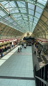 A fast-paced food crawl video featuring various independent food stalls within the Grainger Market in Newcastle, highlighting a range of cuisines from pizza and sushi to Indian street food and coffee.