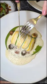 A high-quality, close-up shot of a fine dining dish being cut, showcasing the delicate plating and textures of a Michelin-starred meal at Portland.