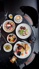 Here are a few options for your alt text, depending on what is most prominent in your specific image:

**Option 1 (Focus on the experience):**
A delicious breakfast spread at Bread Street Kitchen in 22 Bishopsgate with a panoramic view of the London skyline.

**Option 2 (Focus on the food - if it's a close-up):**
Luxury breakfast dishes, including Lobster Benedict, served at Gordon Ramsay’s Bread Street Kitchen in London.

**Option 3 (General/Lifestyle):**
Enjoying a luxury breakfast with a view of London at Bread Street Kitchen, 22 Bishopsgate.

**SEO Tip:** The first option is generally the best for SEO because it includes the location, the restaurant name, and the "London skyline" keyword.