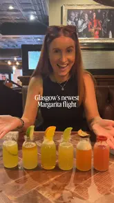 Here are a few options for your SEO alt text, keeping it under 125 characters:

**Option 1 (Descriptive):**
A colorful margarita flight featuring three different cocktails at TGI Fridays in Glasgow.

**Option 2 (Action-focused):**
Close-up of a margarita flight served at TGI Fridays, celebrating May-garita month in Glasgow.

**Option 3 (SEO-focused):**
Three vibrant margaritas in a flight serving tray at a TGI Fridays restaurant in Glasgow.

**Recommendation:** Option 1 is the most balanced for accessibility and SEO.