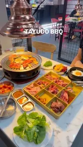 A montage video showcasing an all-you-can-eat Korean BBQ buffet in Birmingham, featuring shots of raw and cooked meats on the grill, various side dishes, the dessert station, and the venue's interior including arcade claw machines.