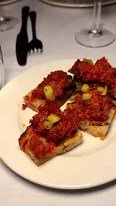 A montage of various dishes served during a special collaboration dinner, featuring Mallorcan-inspired cuisine including sobrasada toast, suckling pig salad, and almond cake.