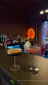 A short, cinematic montage showcasing a cocktail bar in Cheltenham, featuring close-ups of cocktail preparation, the interior ambiance, and live music.
