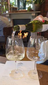 The video is a short, engaging review of a neighbourhood wine bar called Corners in Surbiton. It features shots of the interior, including a fireplace, and highlights various small plates and drinks, such as hake cassoulet, mac and cheese, and pistachio creme brulee.
